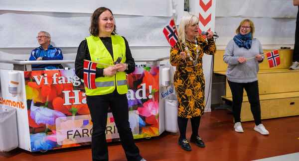Dame med refleksvest og norsk flagg i hånden smiler bredt.
